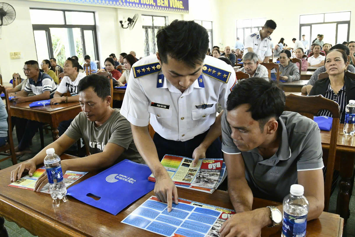 Cán bộ của Hải đoàn 21 phát tờ rơi tuyên truyền IUU và giải đáp thắc mắc cho ngư dân. Ảnh: CV.