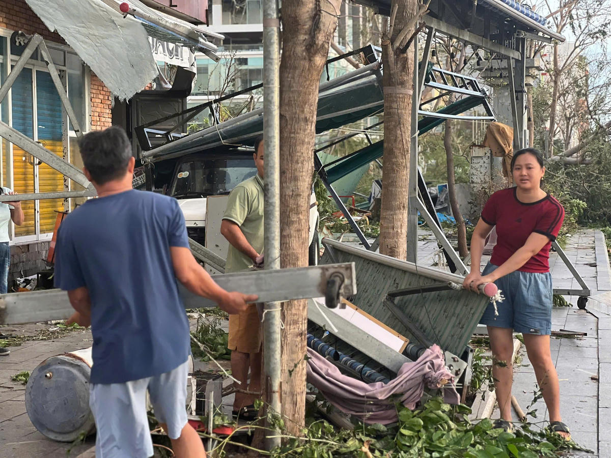 Chị Hà Thị Cẩm Vân cùng chồng dọn dẹp đống đổ nát sau bão số 13. Ảnh Chí Đại.