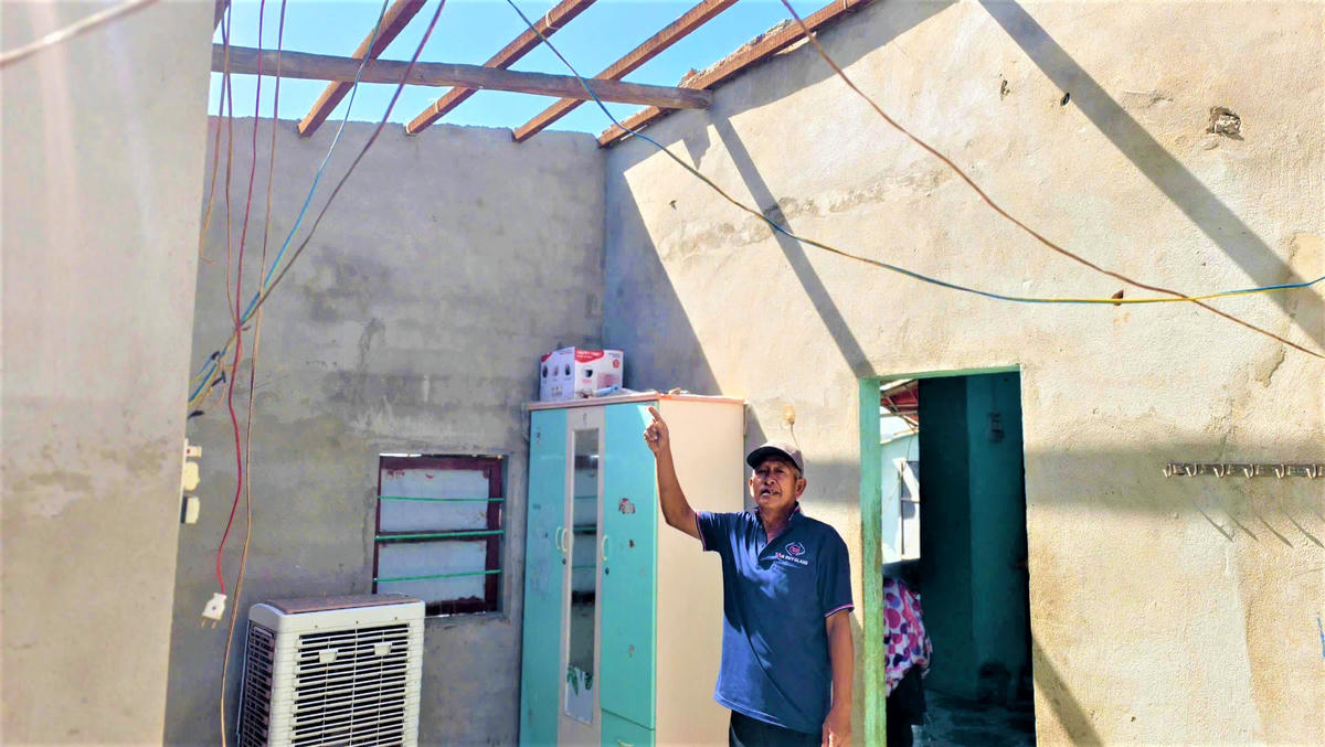 Ông Trần Đình Mai chỉ ngôi nhà bị cơn bão số 13 quét ra hư hỏng nặng. Ảnh: Đình Sang.