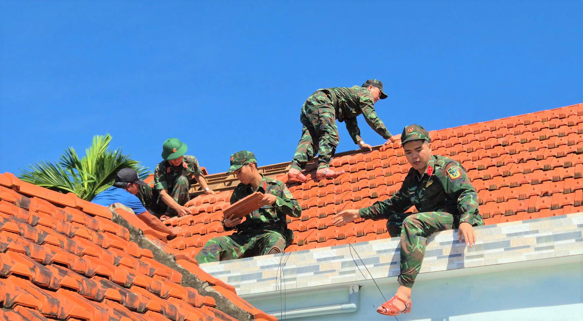 Lực lượng quân đội giúp gia đình ông Ngô Long lợp lại mái nhà. Ảnh: Tấn Thành.