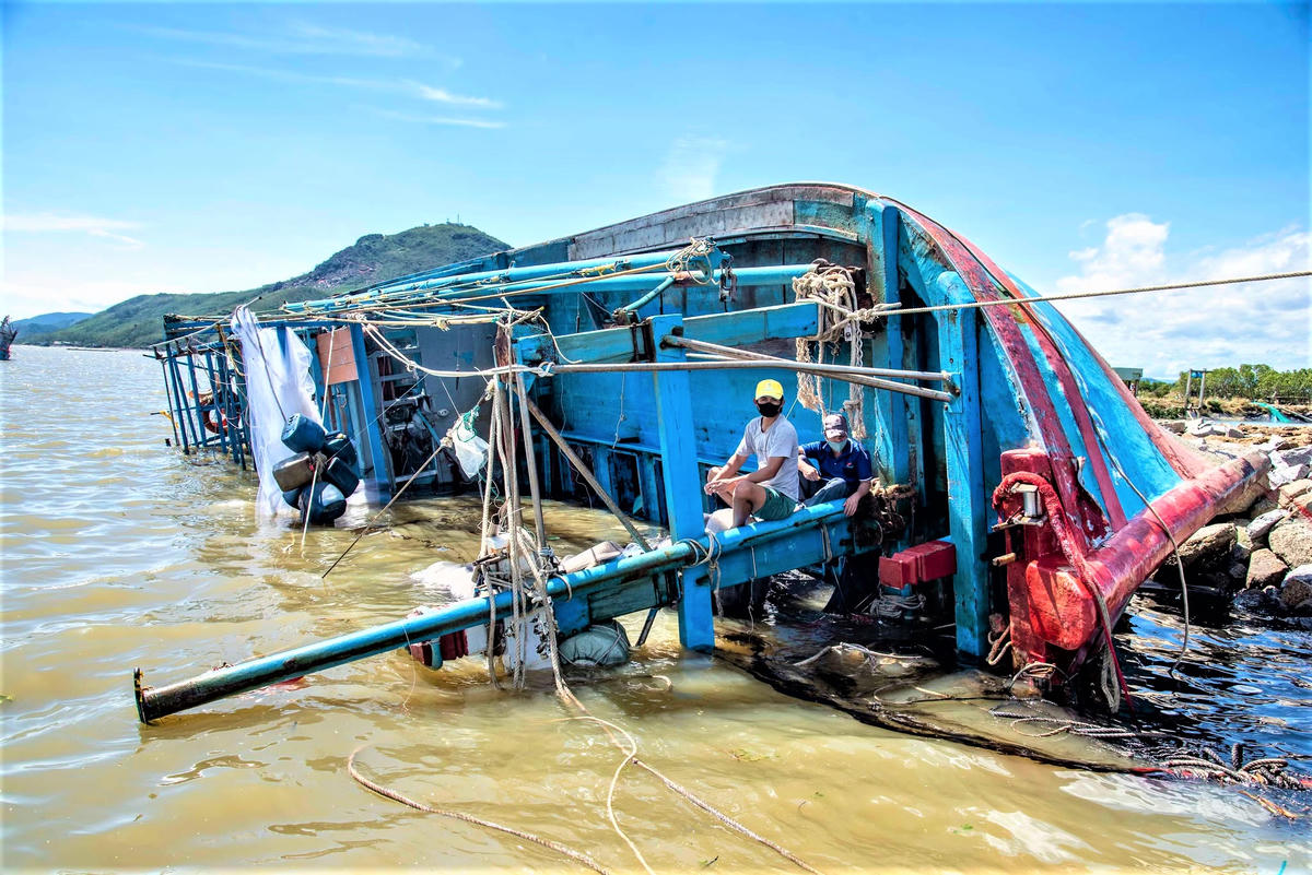 Tàu cá của ngư dân Nguyễn Văn Tý bị sóng biển đánh lật nghiêng. Ảnh: Chí Đại.