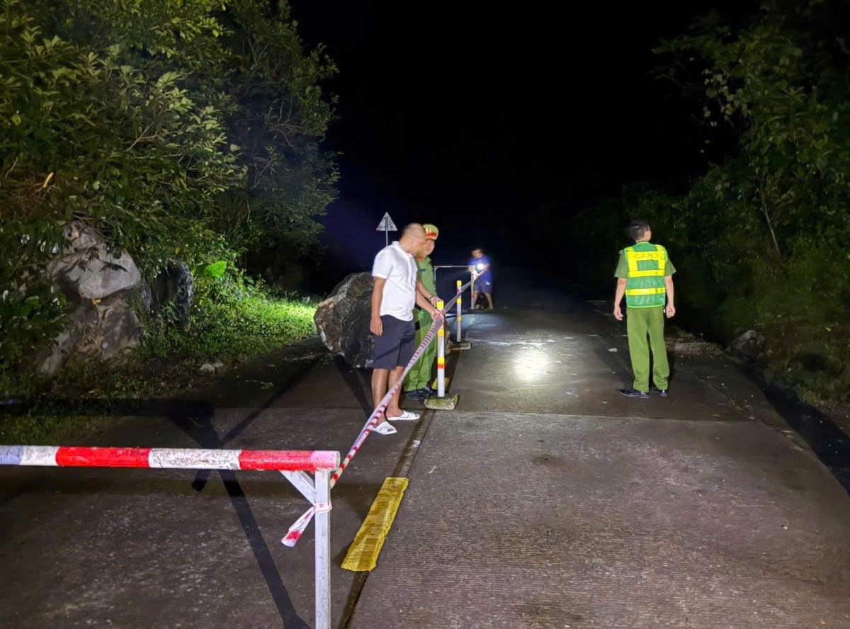 Lực lượng chức năng tiến hành khoanh vùng, đặt cảnh báo ở vị trí tảng đá lăn xuống đường Hồ Chí Minh nhánh tây. Ảnh: UB.