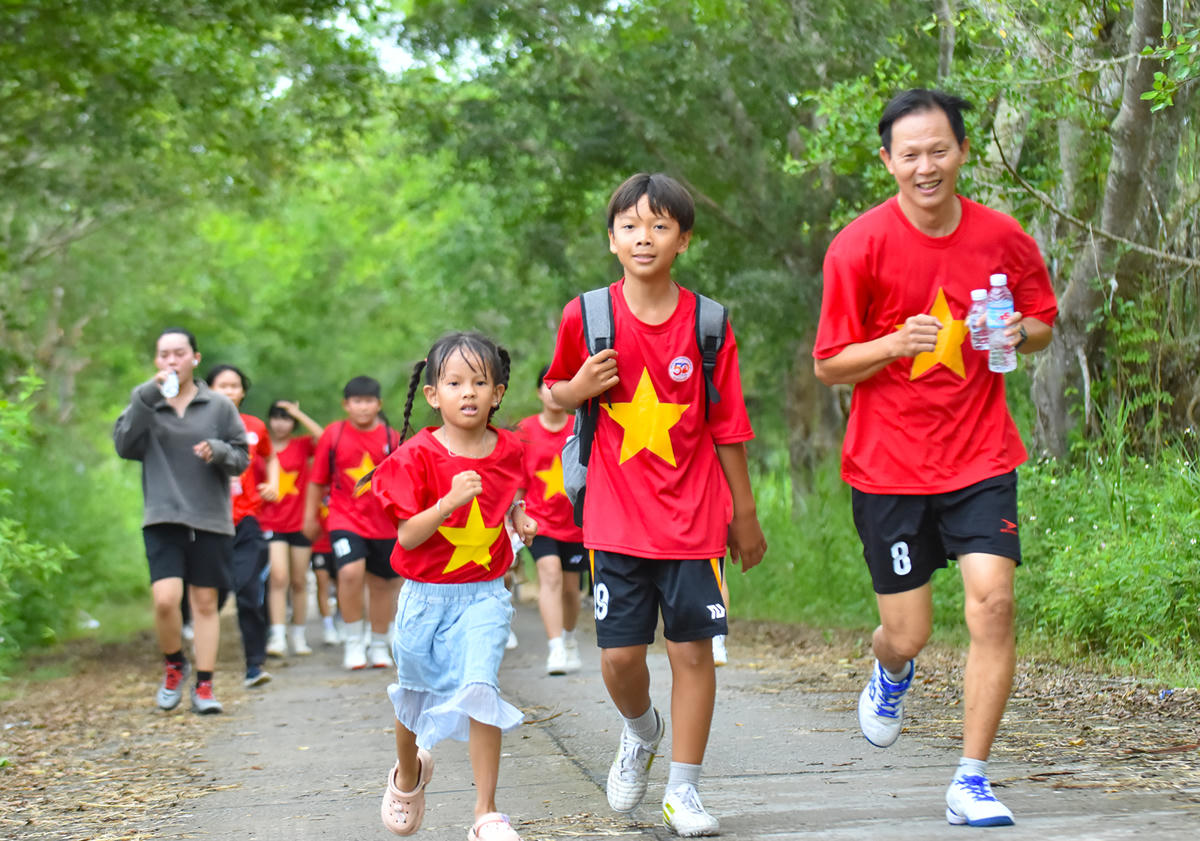 Một em bé tiểu học tham gia giải việt dã cùng anh trai. Ảnh Nguyễn Minh