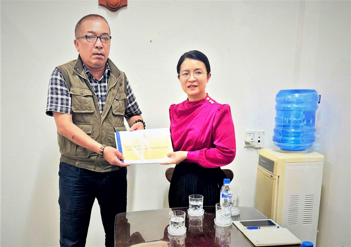 Nhà báo Đinh Tấn Thành đã trao tài liệu thông tin về Giải thưởng “Vinh danh Người truyền lửa”. Ảnh: Nguyễn Tín. 