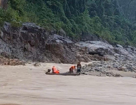 Lực lượng chức năng giải cứu 2 người dân mắc kẹt giữa dòng nước chảy xiết. Ảnh: CV.
