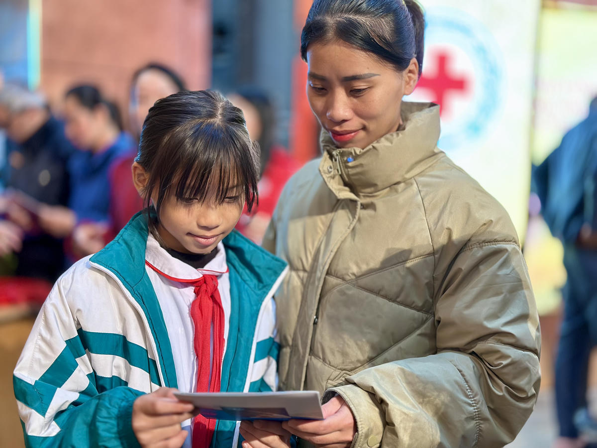 Chị Nguyễn Thị Huệ dặn dò con gái trân trọng tấm thẻ BHYT được tặng. Ảnh: Ngọc Anh.