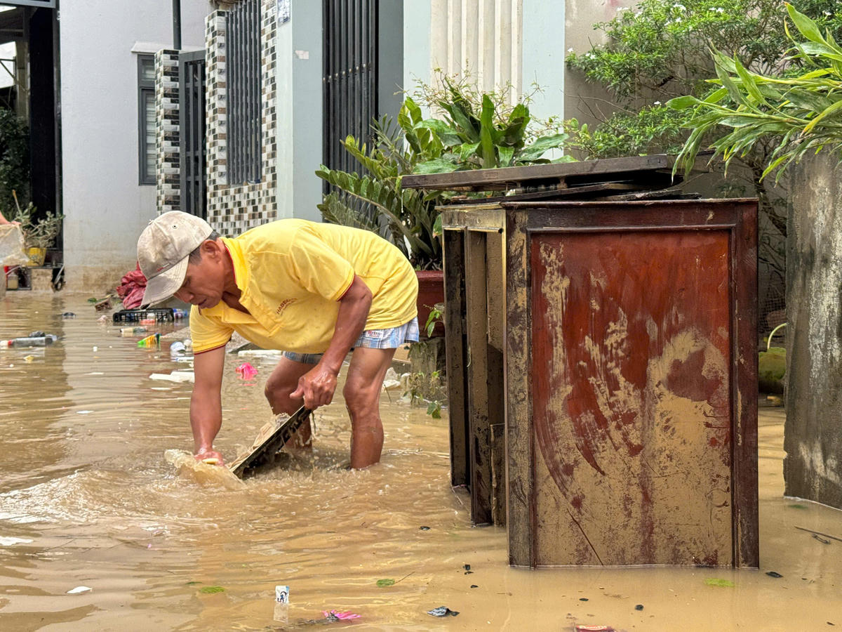 Người dân rửa bùn đất bám vào đồ đạc sinh hoạt trong nhà. Ảnh: C.Đại.