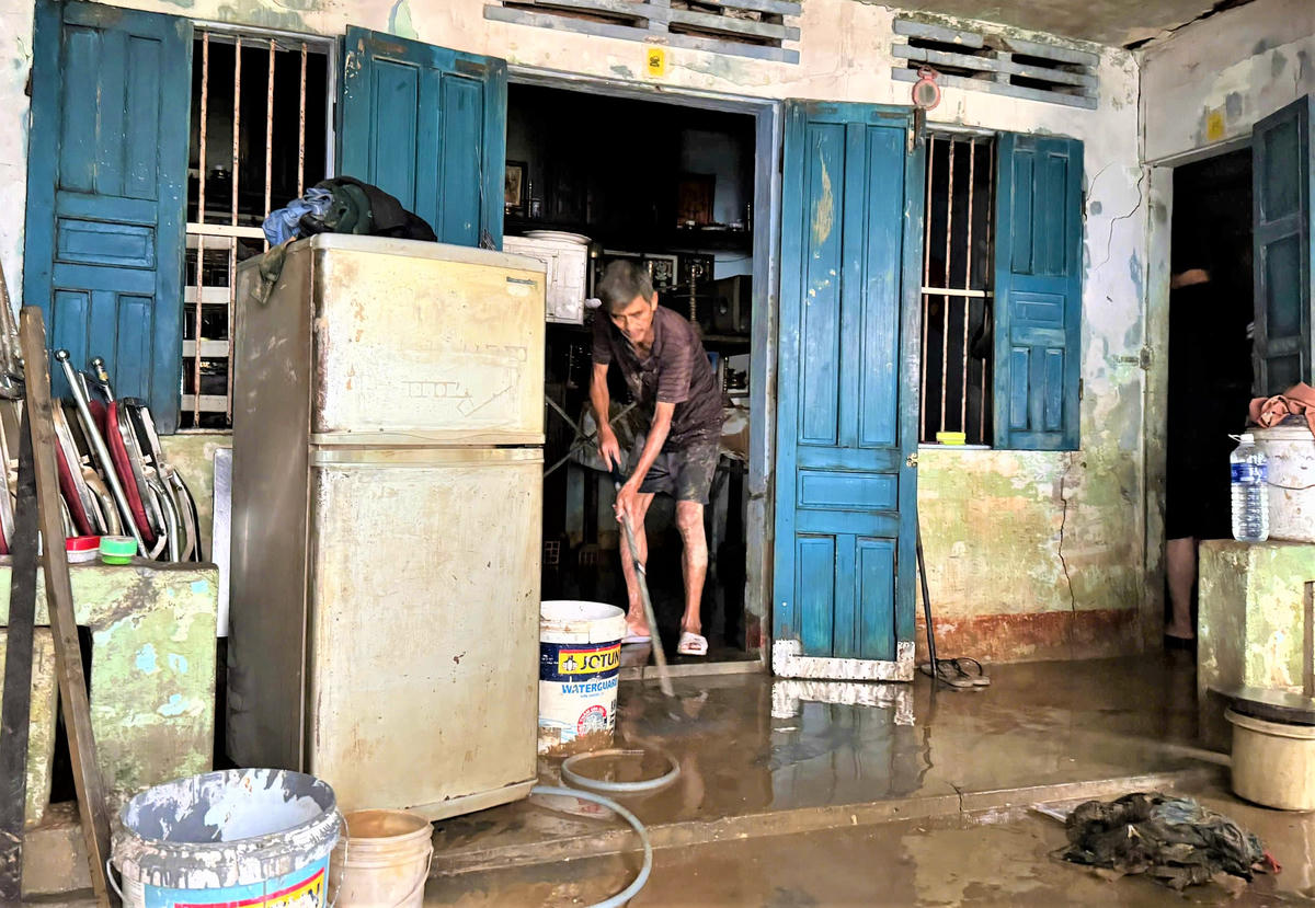 Ông Trần Văn Tiến đang dọn dẹp nhà cửa sau khi lũ rút xuống. Ảnh: T. Thành.