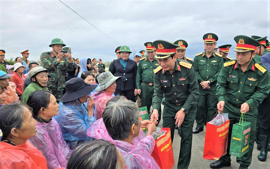 Đại tướng Phan Văn Giang tặng quà cho người dân vùng lụt xã Tuy Phước Đông. Ảnh: T.Thành.