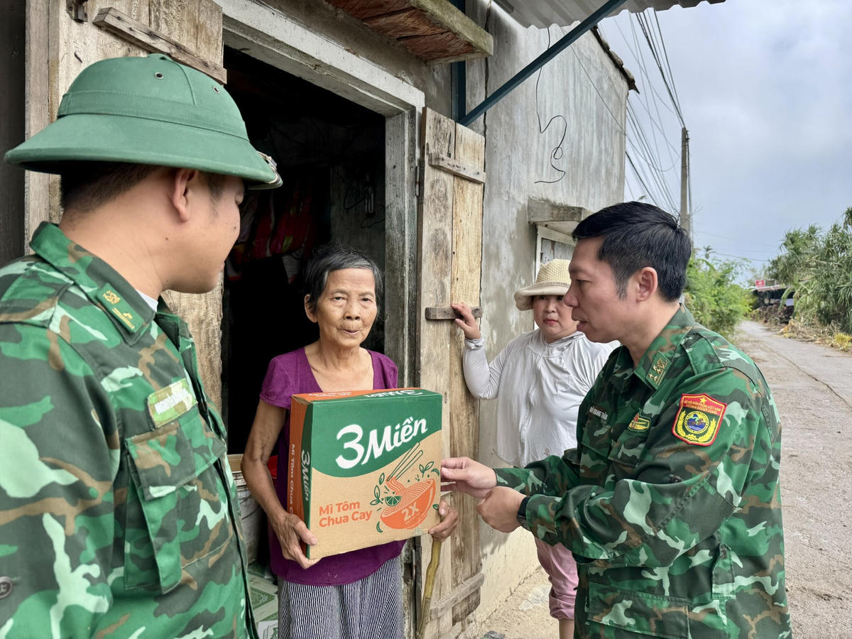 Những người lính dầm mình trong bùn đất, lội nước, đến từng ngõ nhỏ, từng mái nhà để trao tận tay bà con những túi lương thực. Ảnh: Thanh Nga.