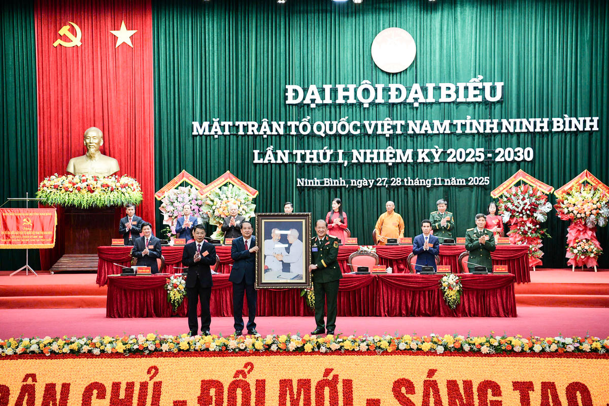 Thượng tướng Bế Xuân Trường tặng đại hội lẵng hoa hoa tươi thắm và bức ảnh 'Bác Hồ bắt tay Bác Tôn'. Ảnh: Trường Giang