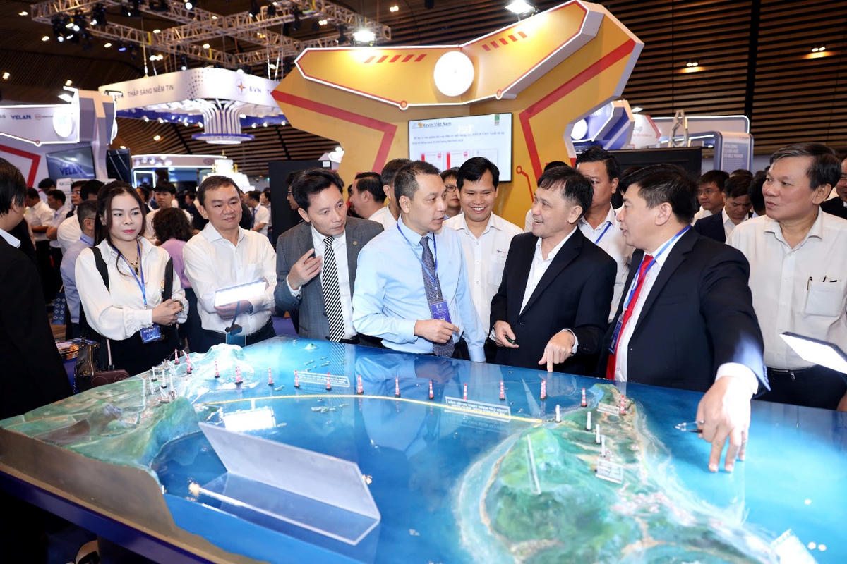 Chủ tịch HĐTV EVN Đặng Hoàng An (áo xanh), ông Mai Quốc Hội - Phó Chủ tịch kiêm Tổng thư ký Hội Điện lực Việt Nam (áo xám) cùng các đại biểu tham quan gian hàng EVNSPC