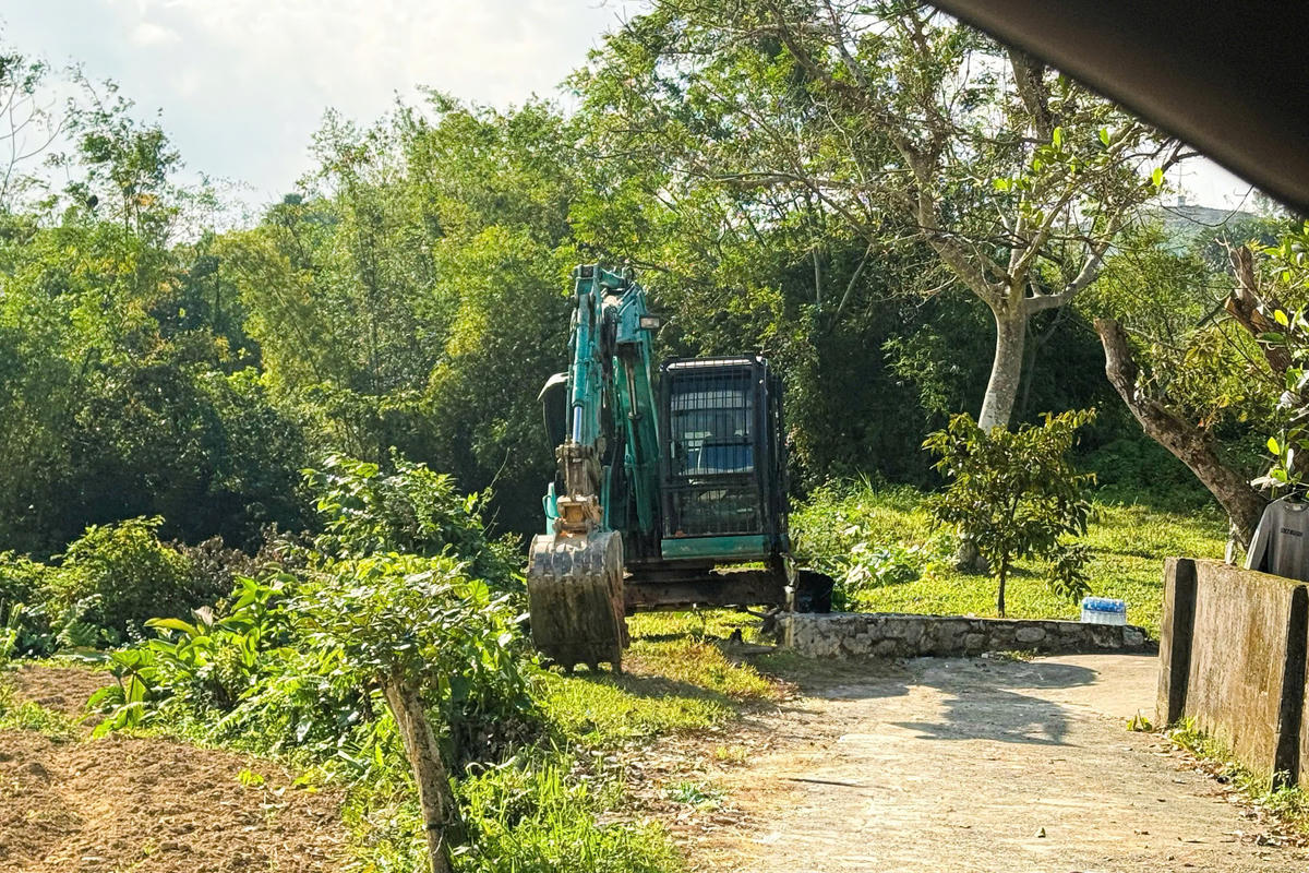 Sau khi phát hiện phóng viên ghi hình, máy múc rời khỏi điểm khai thác và di chuyển vào nhà dân cách 100m. Ảnh: Cẩm Kỳ&nbsp;
