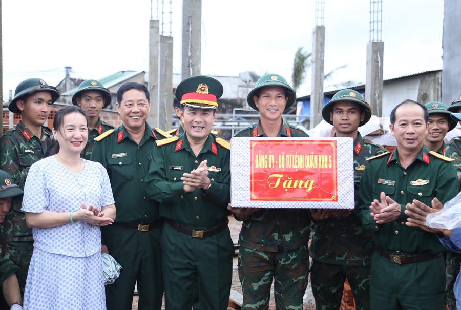 Đại tá Trần Minh Trọng (thứ 3 từ trái sang) thăm, động viên cán bộ, chiến sĩ Quân đoàn 34 đang hỗ trợ gia đình ông Lê Văn Mười xây dựng nhà mới. Ảnh: CV.