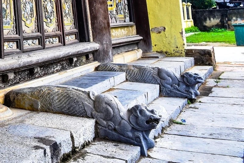 Phía trước bậc tam cấp bước vào nghè là cặp đôi sấu đá được chạm trong tư thế đang chồm tới, đầu hơi ngẩng, mắt lồi, mũi thon, miệng rộng, miệng ngậm viên ngọc quý. Ảnh: Nguyễn Chung.