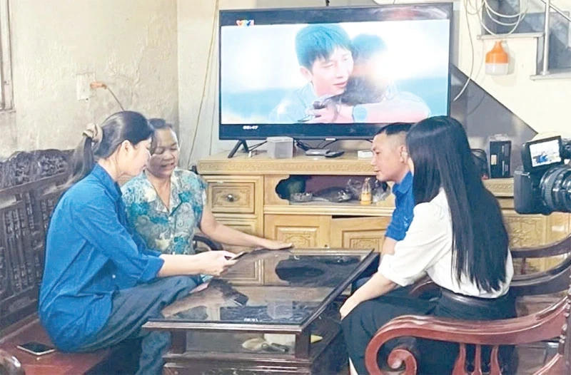 Đoàn viên, thanh niên hỗ trợ người dân thôn Trung Tâm sử dụng điện thoại thông minh để tìm hiểu thông tin, dịch vụ. Ảnh: Lê Hòa