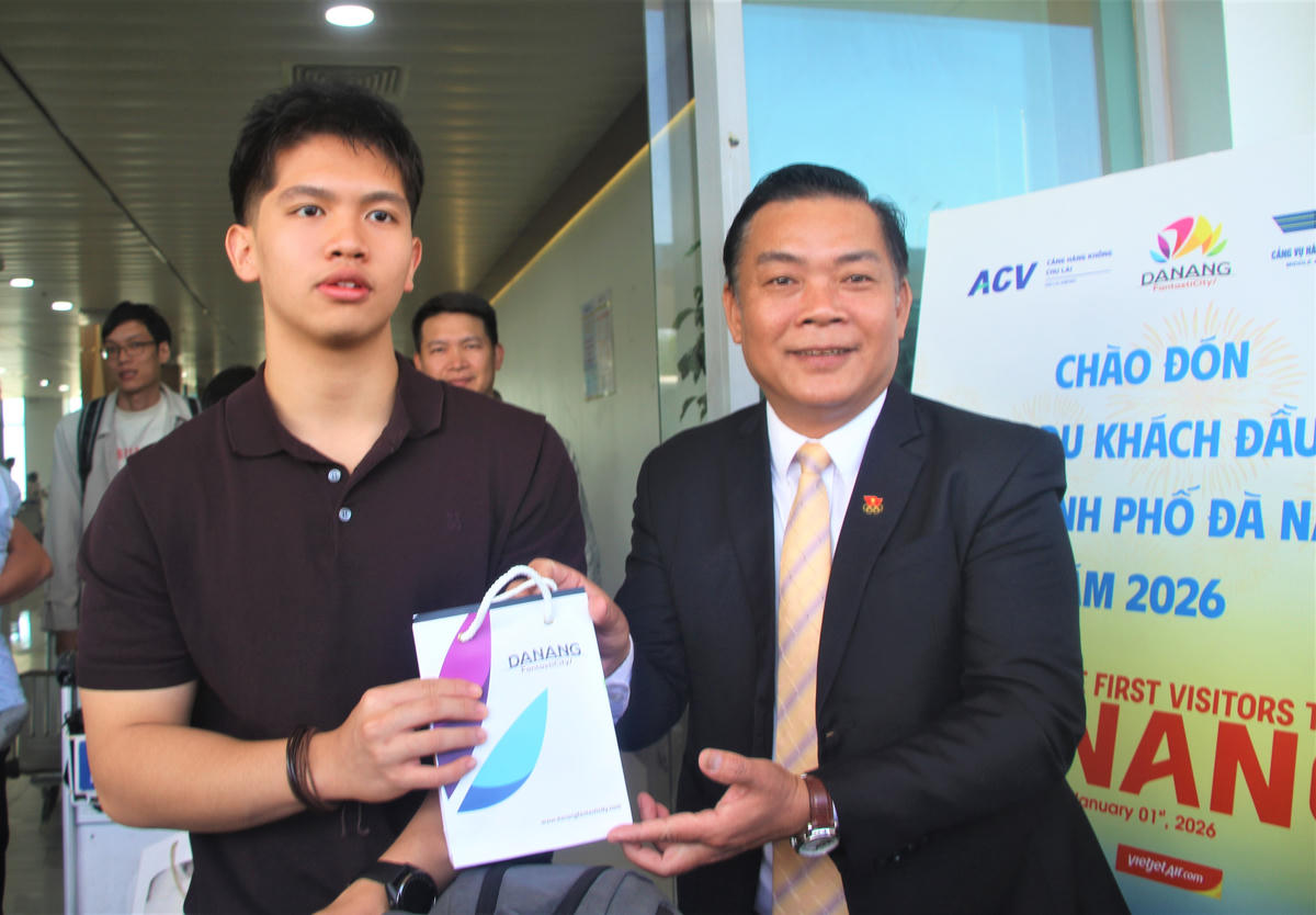 Ông Tào Viết Hải, Phó Sở VHTTDL TP Đà Nẵng tặng quà cho hành khách trên chuyên bay hãng hàng không Vietnam Airlines. Ảnh: Chí Đại.