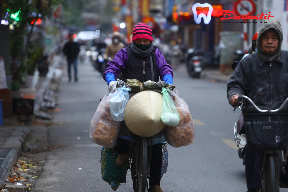 Nhiều người dân bán hàng tại chợ Hà Đông quấn khăn kín cổ hoặc mặc áo mưa trùm ngoài áo ấm, tay chân tê buốt vẫn cố gắng buôn bán để kịp phiên chợ sớm.