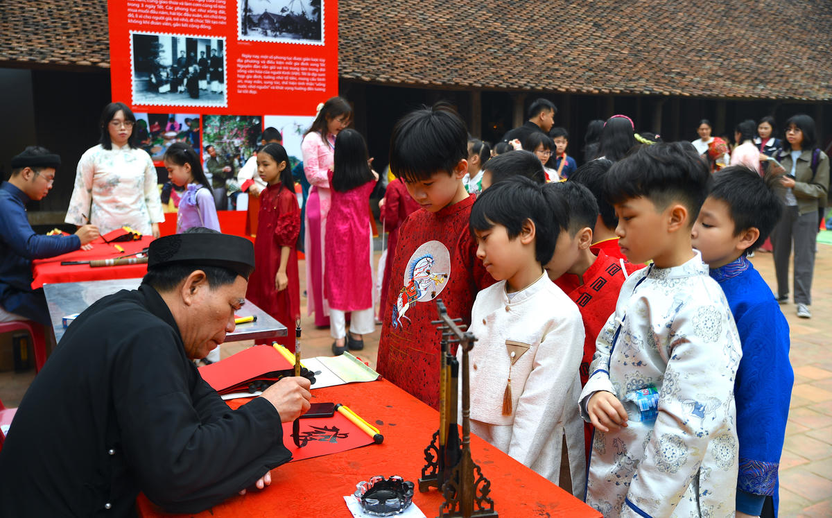 Các em nhỏ trải nghiệm viết thư pháp và xin chữ, một nét đẹp đầu xuân. Ảnh: Phạm Sỹ.