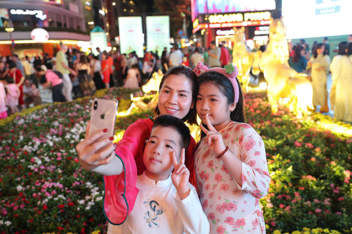 Các gia đình, nhóm bạn trẻ, du khách quốc tế diện áo dài truyền thống, tranh thủ ghi lại những khoảnh khắc đầu năm mới bên tiểu cảnh linh vật, đại cảnh hoa xuân và các mô hình trang trí công phu.