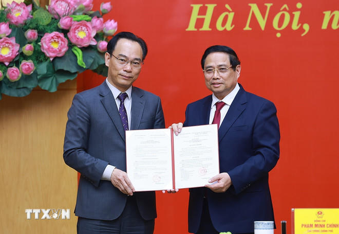 Thủ tướng Phạm Minh Chính trao Quyết định của Thủ tướng Chính phủ về việc điều động ông Hoàng Minh Sơn, Giám đốc Đại học Quốc gia Hà Nội, về công tác tại Bộ Giáo dục và Đào tạo, giao Quyền Bộ trưởng Bộ Giáo dục và Đào tạo. (Ảnh: Dương Giang/TTXVN).