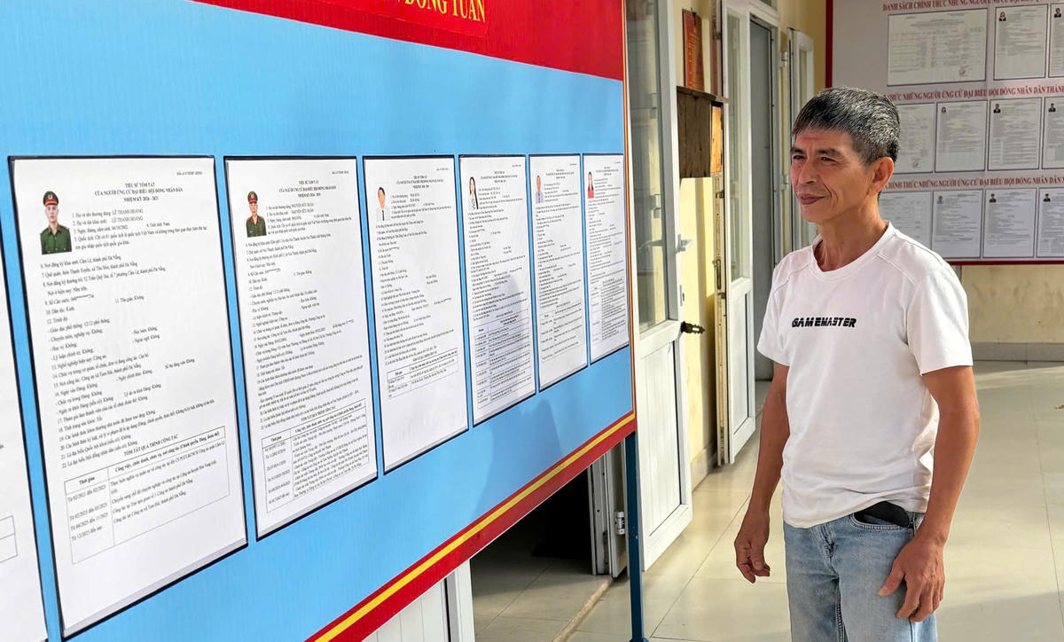 Ngư dân Lê Văn Long đang xem danh sách ứng cử viên ĐBQH khóa XIV. Ảnh: Nguyễn Tín.