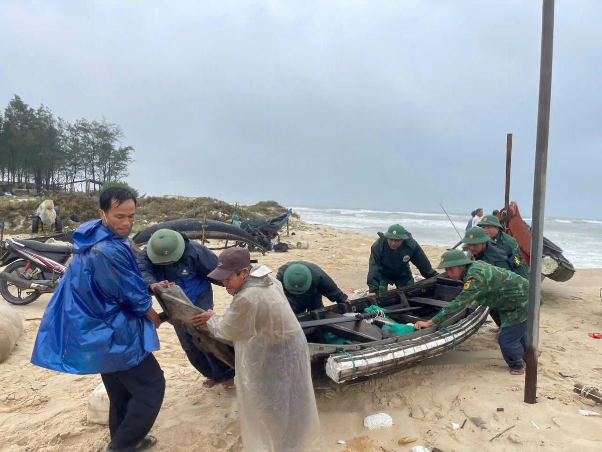 Bộ đội Biên phòng cùng bà con nhân dân nhanh chống vận chuyển ghe, ngư lưới cụ dọc bờ biển lên các vị trí an toàn. Ảnh: BPQT.