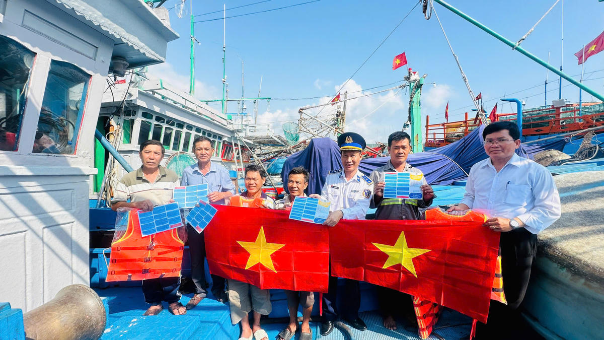 Thượng tá Phan Văn Hiếu trao quà và tặng cờ Tổ quốc cho ngư dân phường Hoài Nhơn Bắc. Ảnh: CV.