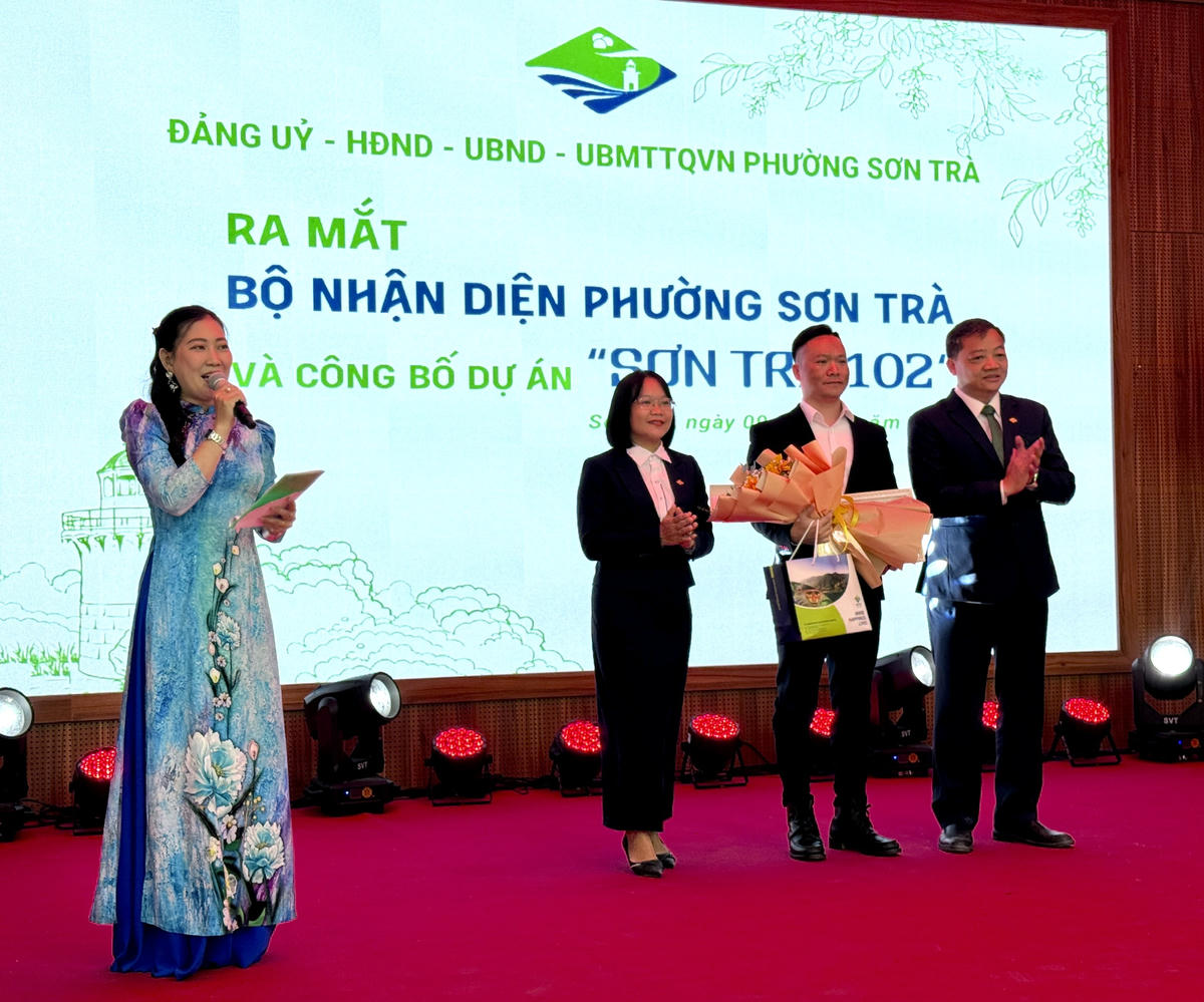 Ông Đinh Vui, Chủ tịch UBND phường, bà Phan Thị Nữ, Phó Bí thư Thường trực Đảng ủy phường tặng hoa cảm ơn tác giả Đào Anh Tài. Ảnh: Nguyễn Tú.