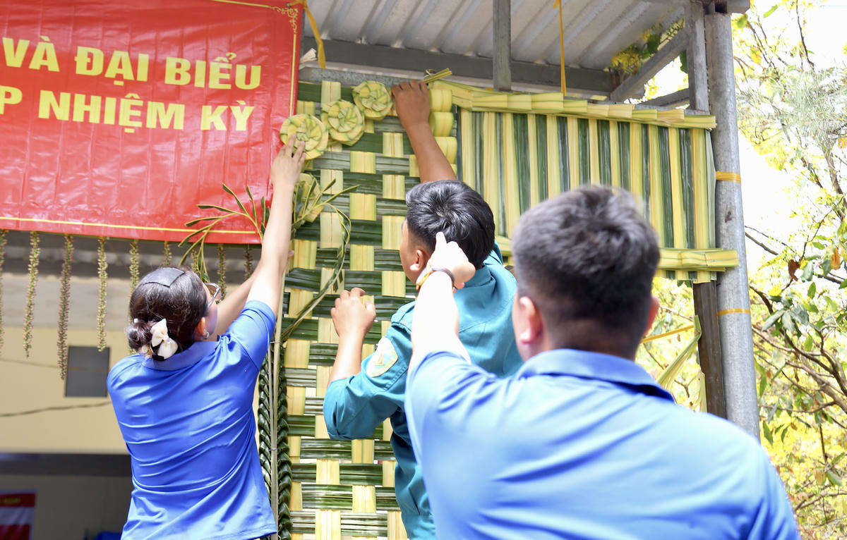 Đoàn viên, thanh niên xã Vĩnh Bình tham gia trang trí điểm bỏ phiếu tại ấp&nbsp;Hiệp Hoà bằng lá dừa và các loại cây lá có sẵn tại địa phương. Ảnh: Thanh Tiến