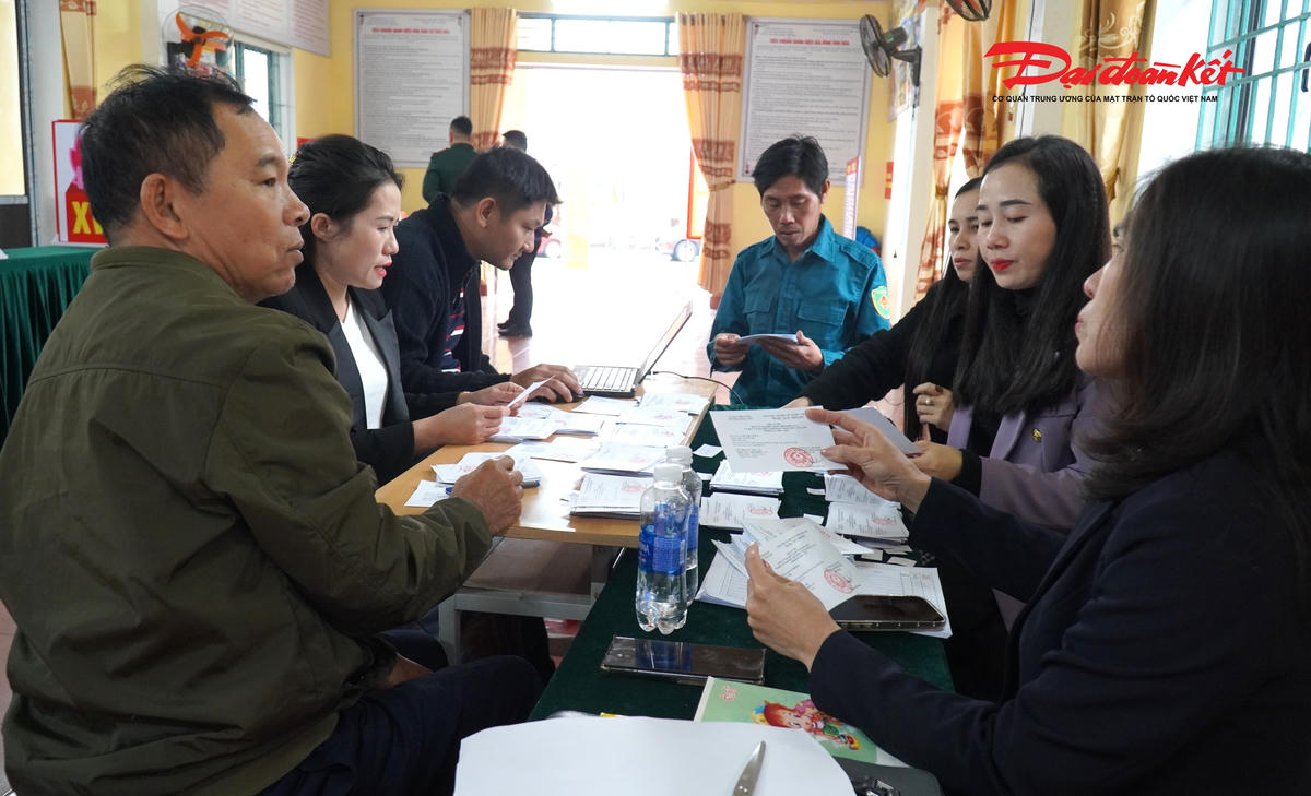 Bên trong nhà văn hóa tổ dân phố Liên Giang, không khí làm việc khá nhộn nhịp. Những chiếc bàn dài được kê sát nhau, trên bàn là các tập giấy, danh sách cử tri và phiếu bầu được sắp xếp thành từng chồng nhỏ.
Các cán bộ tổ dân phố, công an, quân sự và cán bộ phường cùng ngồi rà soát lại từng thông tin, chuẩn bị cho ngày bầu cử. Ở phía trước hội trường, chiếc hòm phiếu được cán bộ quân sự kiểm tra lại phần nắp, gia cố chắc chắn trước khi trang trí theo đúng quy định.