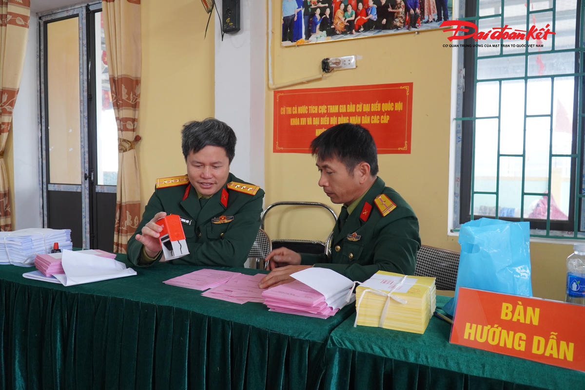 Ở một góc khác, hai cán bộ thuộc lực lượng quân sự cẩn thận đóng dấu lên từng lá phiếu bầu cử. Những con dấu đỏ lần lượt hiện lên, từng tập phiếu được xếp gọn gàng chờ chuyển sang khâu tiếp theo.