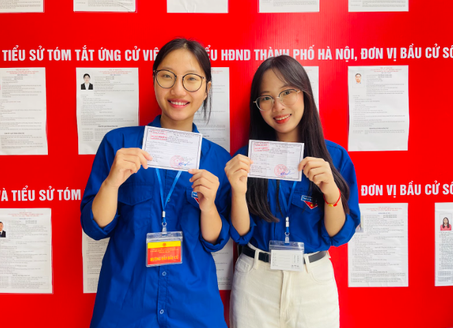 Hai cử tri trẻ chụp ảnh với phiếu bầu sau khi hoàn thành thủ tục tại khu vực bỏ phiếu số 4.