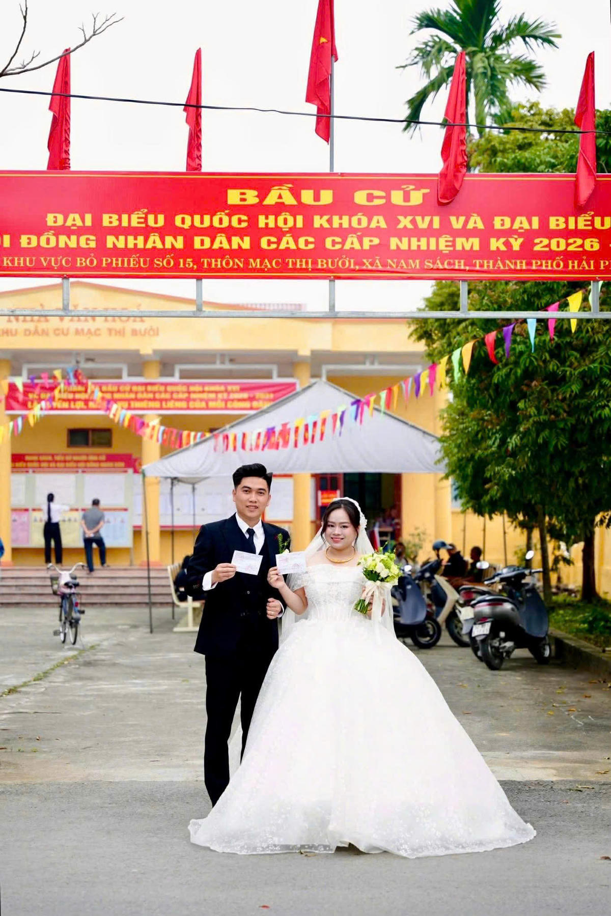 Đôi vợ chồng trẻ đã cùng nhau chụp ảnh lưu niệm tại cổng khu vực bầu cử, lưu giữ dấu ấn đặc biệt của một ngày vừa thiêng liêng đối với cuộc đời họ. Ảnh: TĐ. 