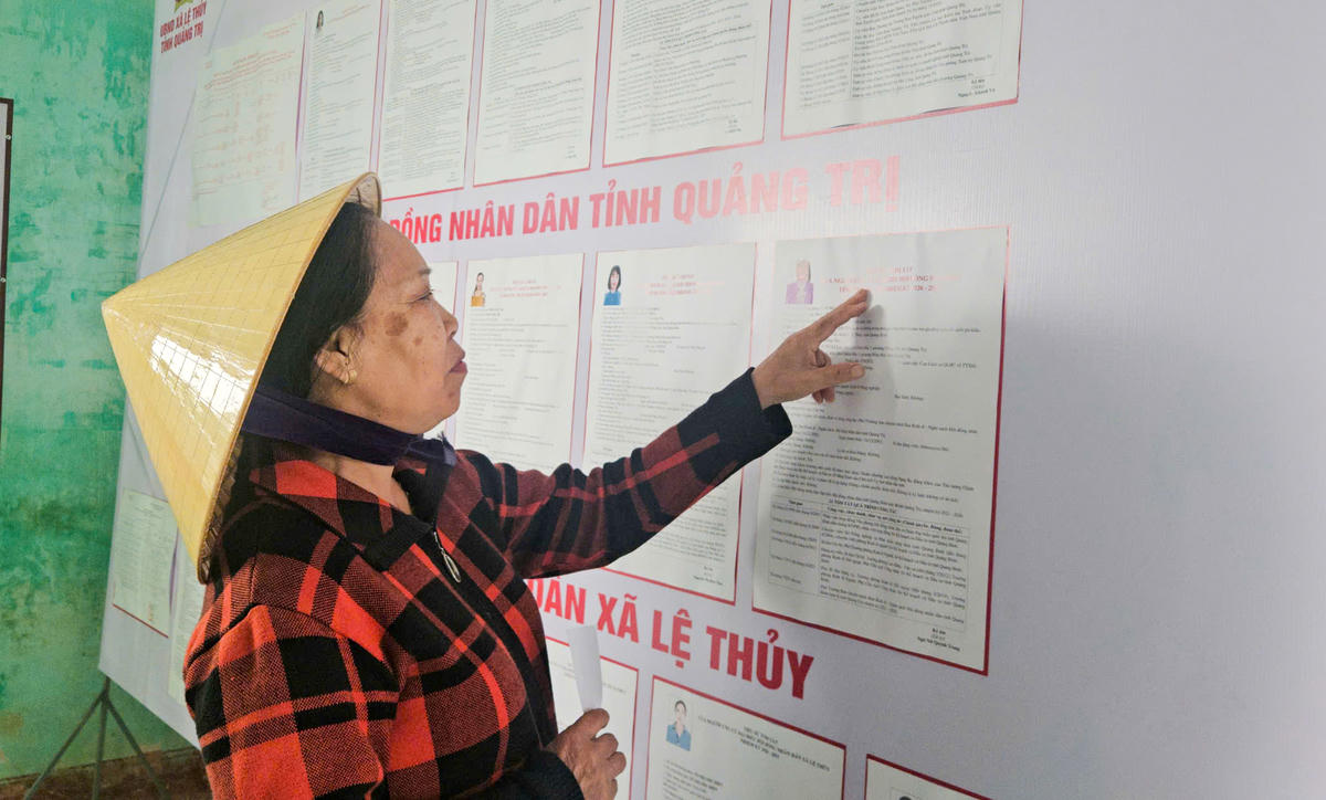 Bà Nguyễn Thị Thắm hoàn thành vài mũi kim cuối cùng rồi tranh thủ đến điểm bỏ phiếu. Ảnh: Cẩm Kỳ