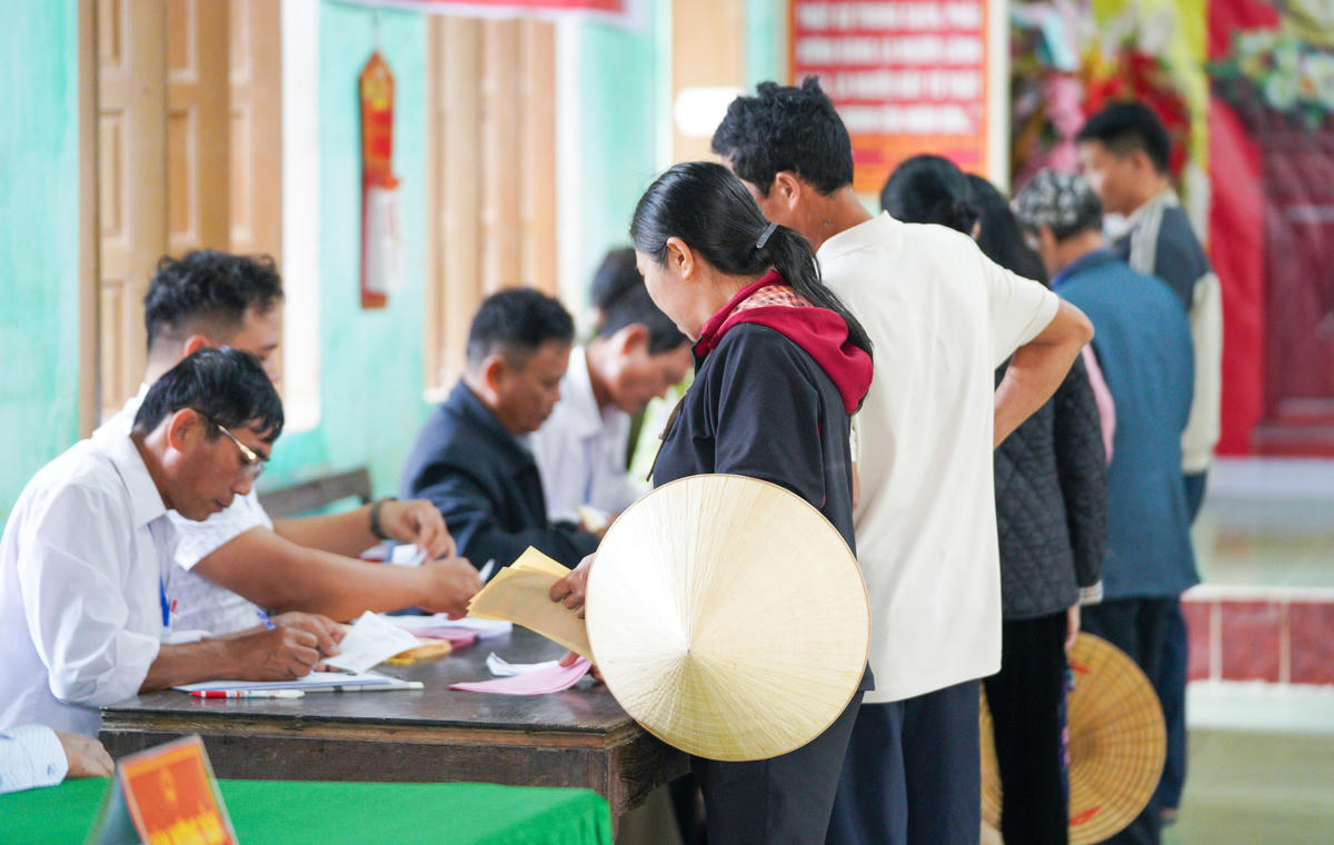 Các cử tri ký tên vào danh sách, nhận phiếu và bỏ phiếu vào hòm. Ảnh: Cẩm Kỳ