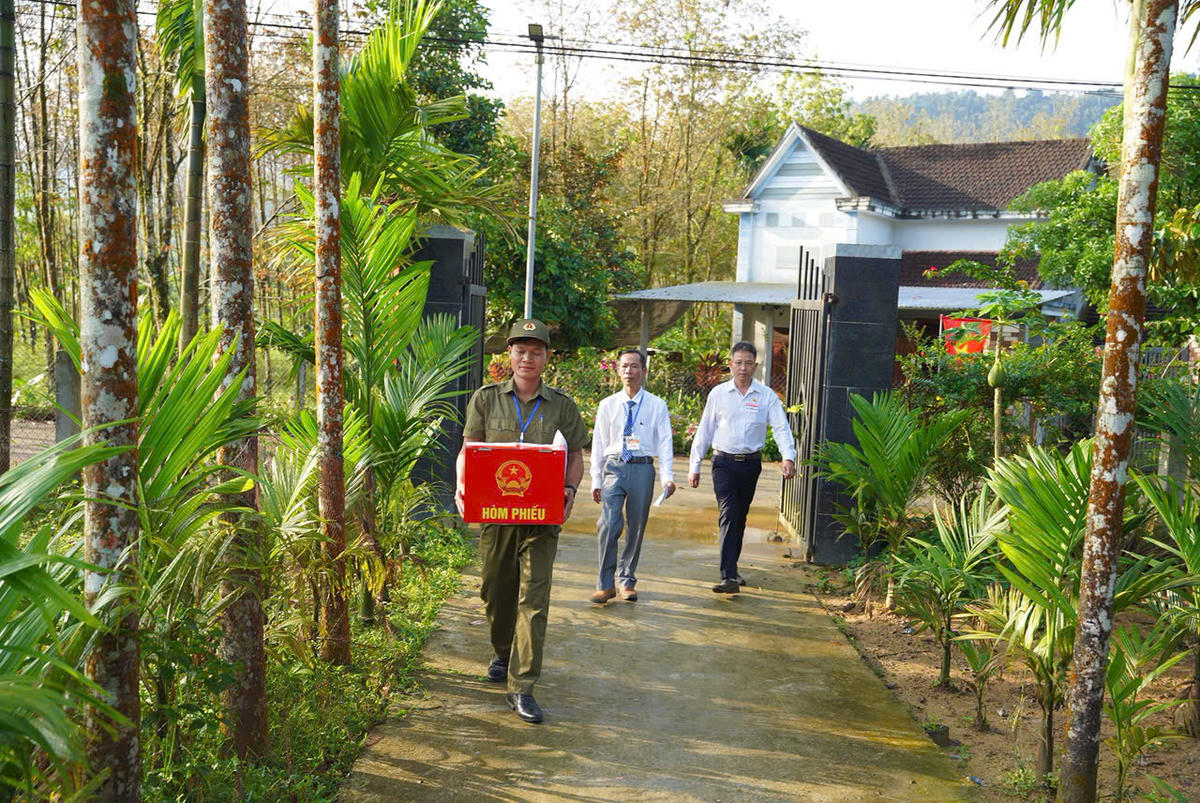 Cán bộ xã Trà Tân mang hòm phiếu đển từng nhà cử tri già yếu. Ảnh: CV.