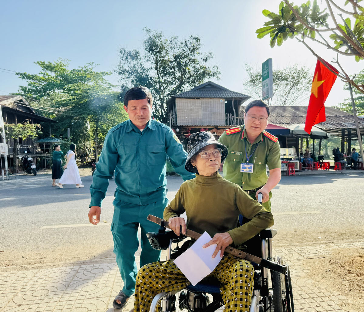 Cư tri H' Nghiệp Knul ở Buôn Trí được lực lượng Công an xã hỗ trợ đến điểm bỏ phiếu để&nbsp; thực hiện quyền và nghĩa vụ công dân. Ảnh: Thanh Nga.
