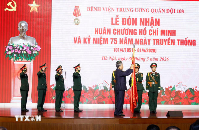Tổng Bí thư Tô Lâm, Bí thư Quân ủy Trung ương gắn Huân chương Hồ Chí Minh lên Quân kỳ Quyết thắng của Bệnh viện Trung ương Quân đội 108. (Ảnh: Thống Nhất/TTXVN).
