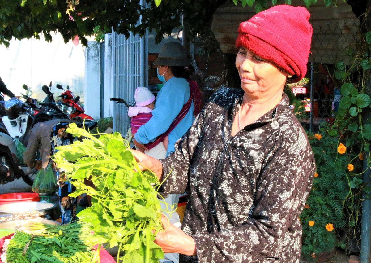 Nụ cười khi người dân mua bó rau ở trên đường Hai Bà Trưng. Ảnh: C.Đ.