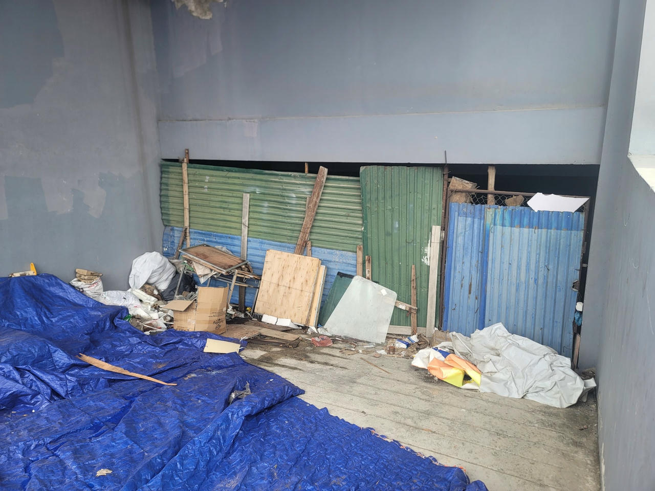 Lối đi xuống tầng hầm phủ đầy rác thải bẩn thỉu, được bịt kín bằng tôn thép.