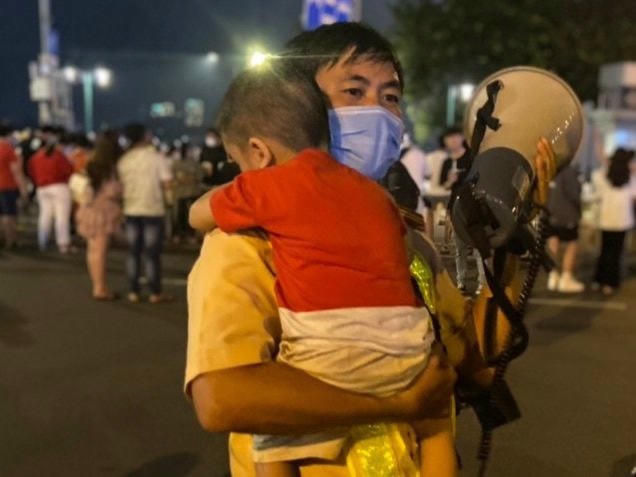 Đồng chí Thiếu tá Đinh Minh Vương đang phát loa tìm cha mẹ bé trai.