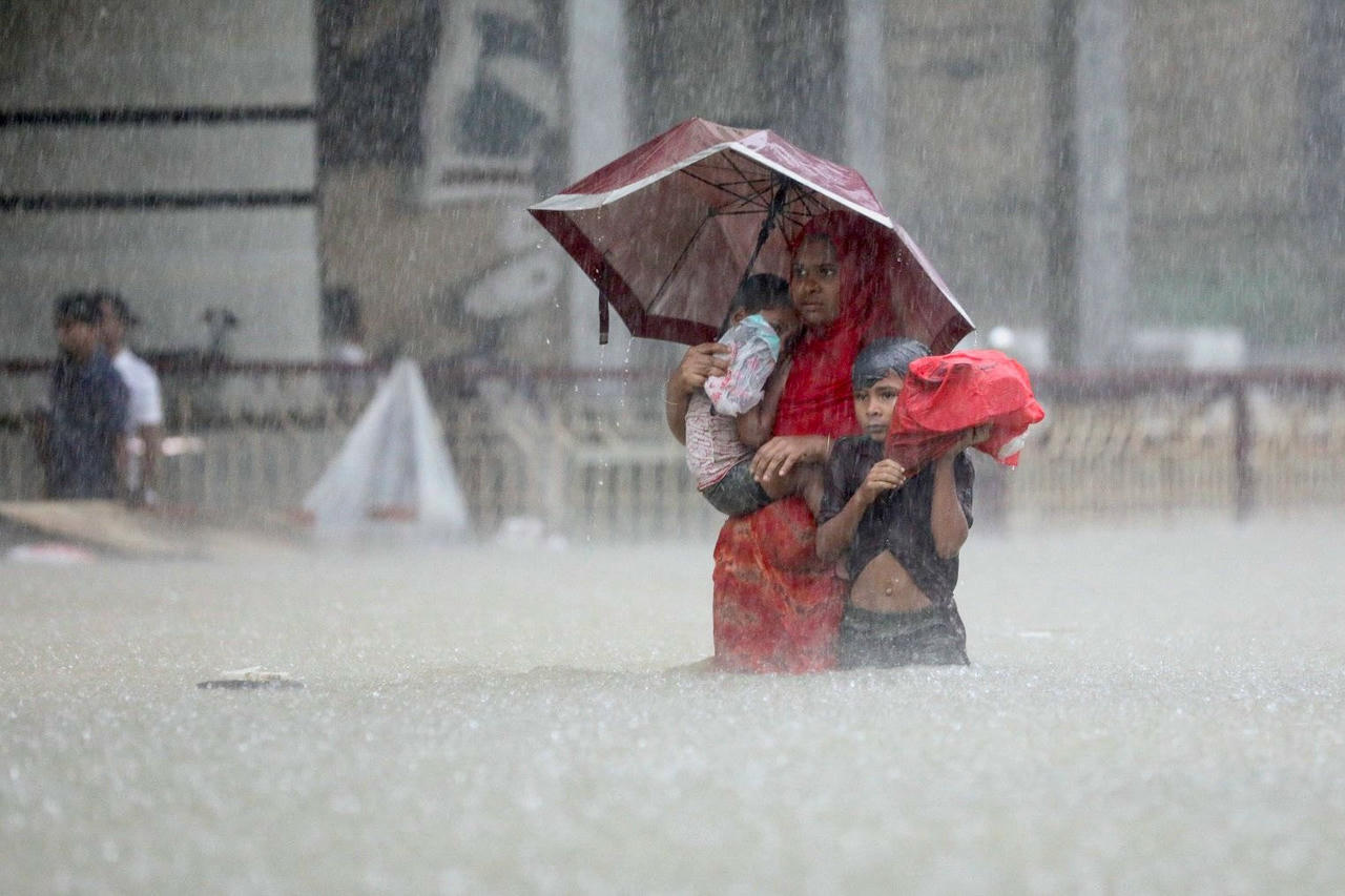 Mọi người lội qua dòng nước khi tìm nơi trú ẩn trong trận lũ lụt ở Sylhet, Bangladesh. Ảnh: Reuters.