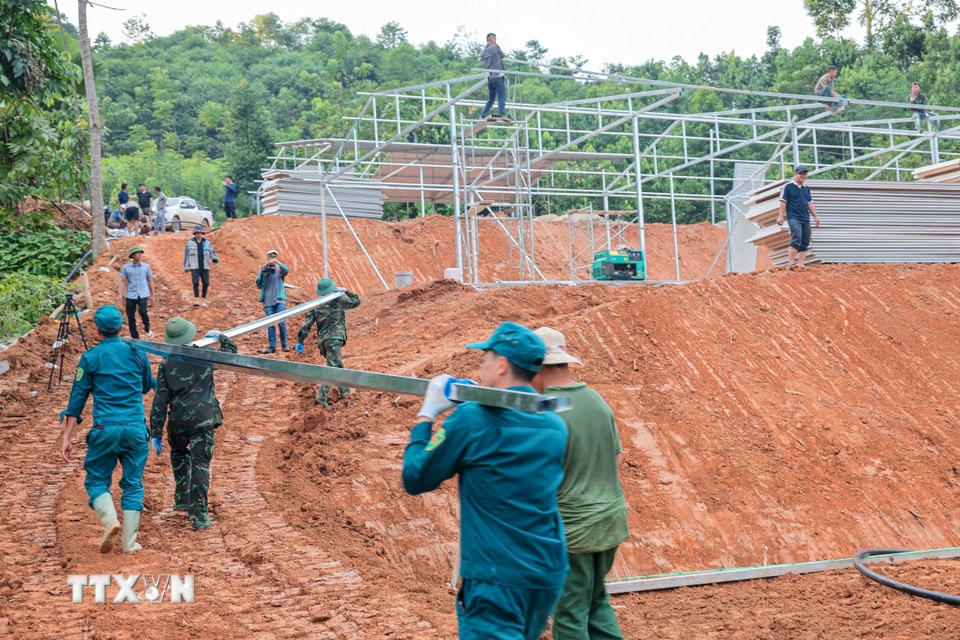 Lực lượng dân quân tự vệ hỗ trợ chuyển vật liệu thi công xây lắp nhà tạm khu tái định cư mới cho người dân thôn Làng Nủ, xã Phúc Khánh, huyện Bảo Yên, tỉnh Lào Cai. (Ảnh: Hoàng Hiếu/TTXVN)