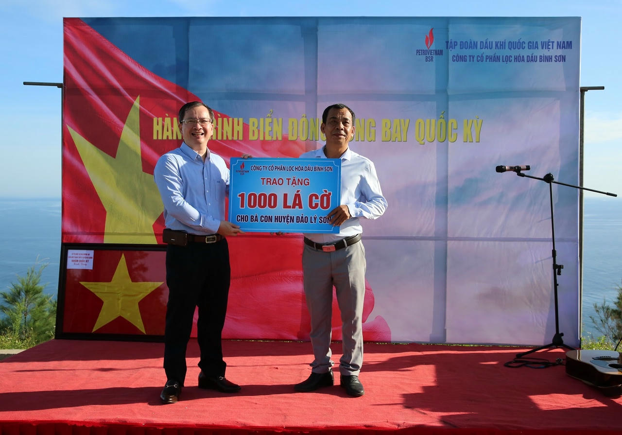 Ông Khương Lê Thành - Phó Bí thư thường trực Đảng uỷ, Thành viên HĐQT, Chủ tịch HCCB BSR trao bảng tượng trưng 1.000 lá cờ Tổ quốc cho ông Nguyễn Văn Sơn - Ủy viên Ban Thường vụ Huyện uỷ, Phó chủ tịch Hội đồng nhân dân huyện.