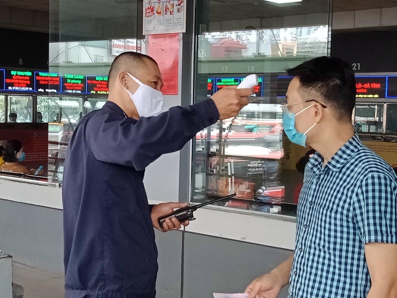 Một nam hành khách đang được kiểm tra thân nhiệt.
