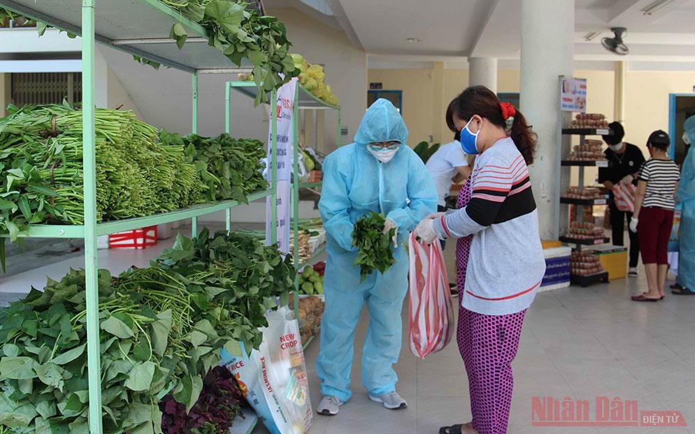 Tình nguyện viên mặc đồ bảo hộ hỗ trợ người dân chọn hàng.
