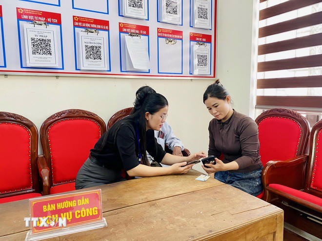 Lãnh đạo Trung tâm phục vụ hành chính công xã Kỳ Thượng (tỉnh Hà Tĩnh) trực tiếp hướng dẫn người dân đăng ký hồ sơ trực tuyến. (Ảnh: Hữu Quyết/TTXVN).