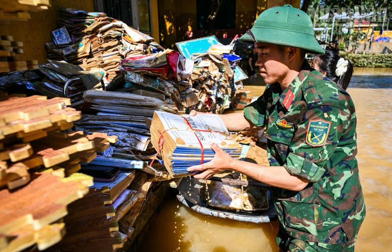 Các chiến sĩ bộ đội giúp thu dọn tại điểm trường bị ngập úng.