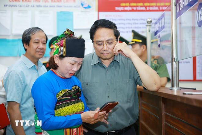 Thủ tướng Phạm Minh Chính thăm hỏi nhân dân đến làm thủ tục tại Trung tâm Phục vụ hành chính công xã Bát Mọt, tỉnh Thanh Hóa. (Ảnh: Dương Giang/TTXVN)